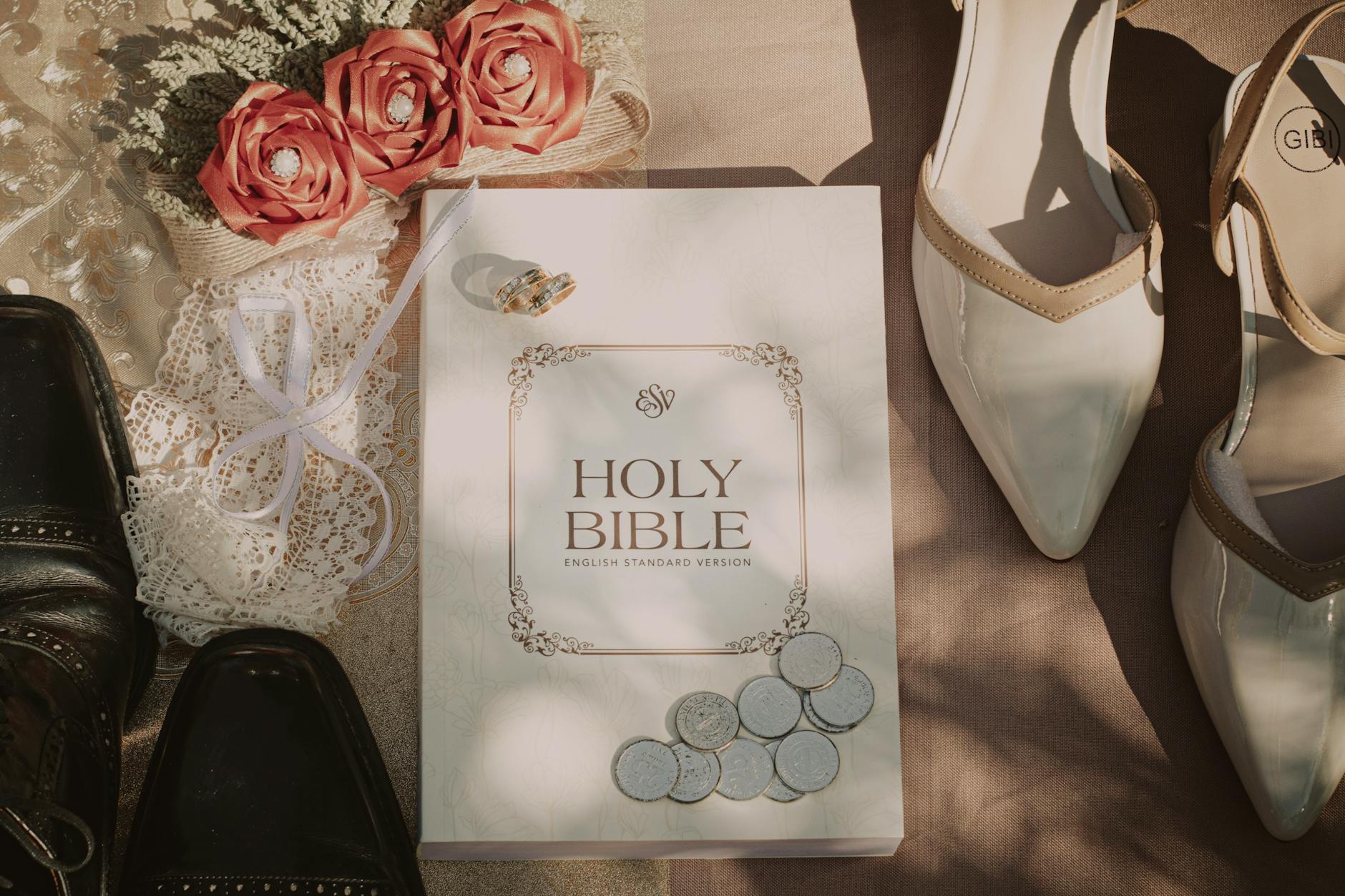 Flat lay of wedding accessories with Holy Bible, shoes, and floral arrangement.