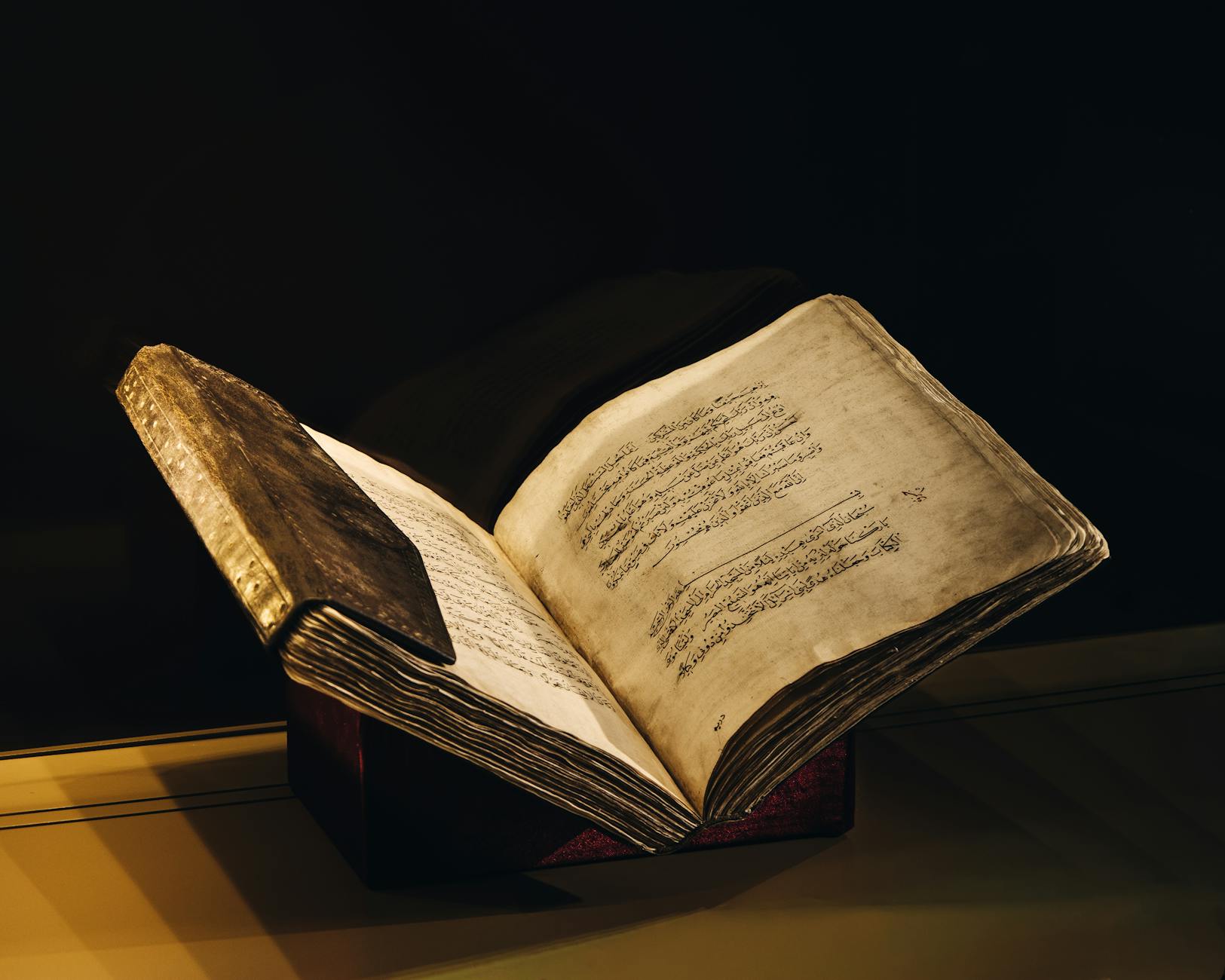 A vintage manuscript with Arabic script open to reveal beautifully aged pages, showcased elegantly.