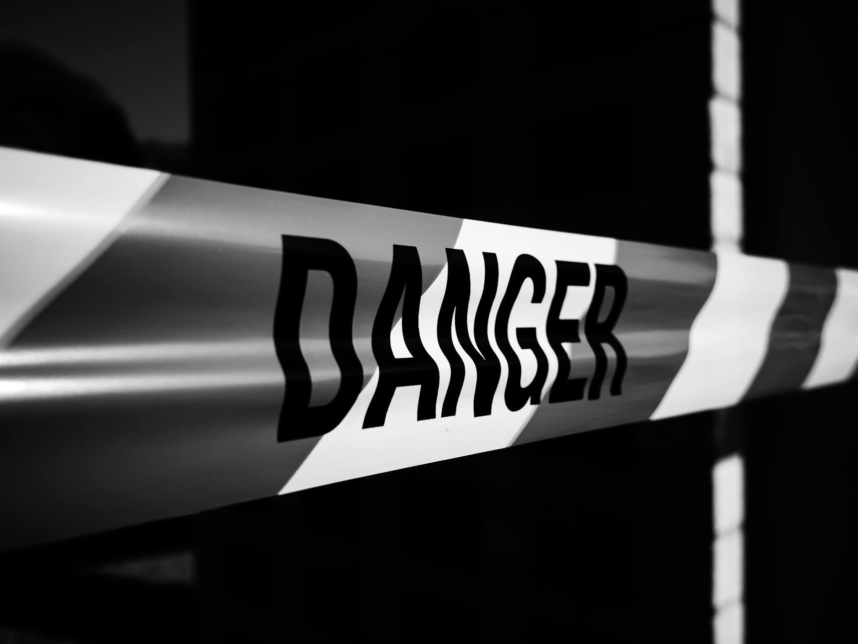 Close-up of a danger tape in black and white, emphasizing caution and warning.