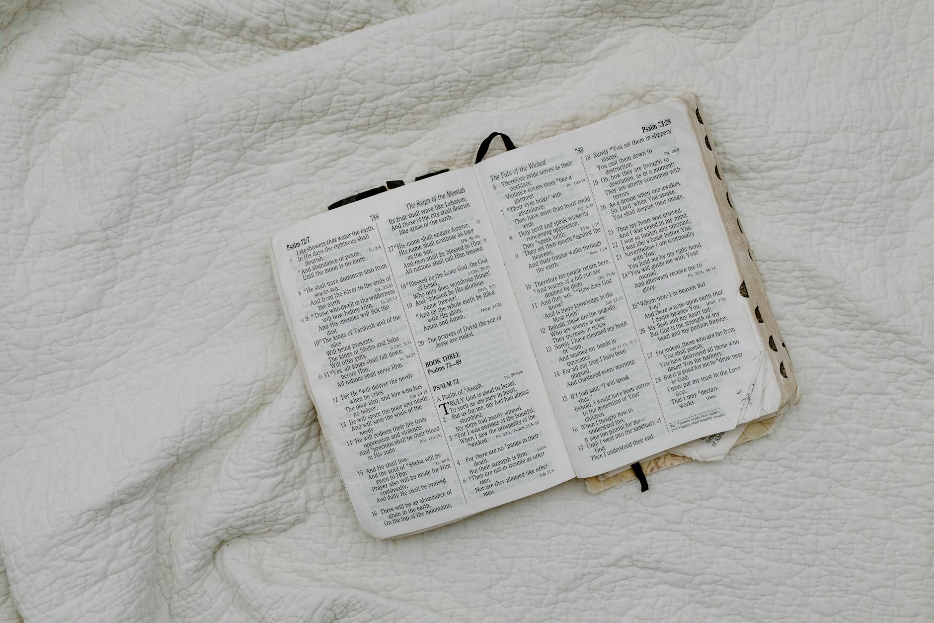 An overhead shot of an open Bible resting on a soft quilt, evoking a peaceful and contemplative atmosphere.